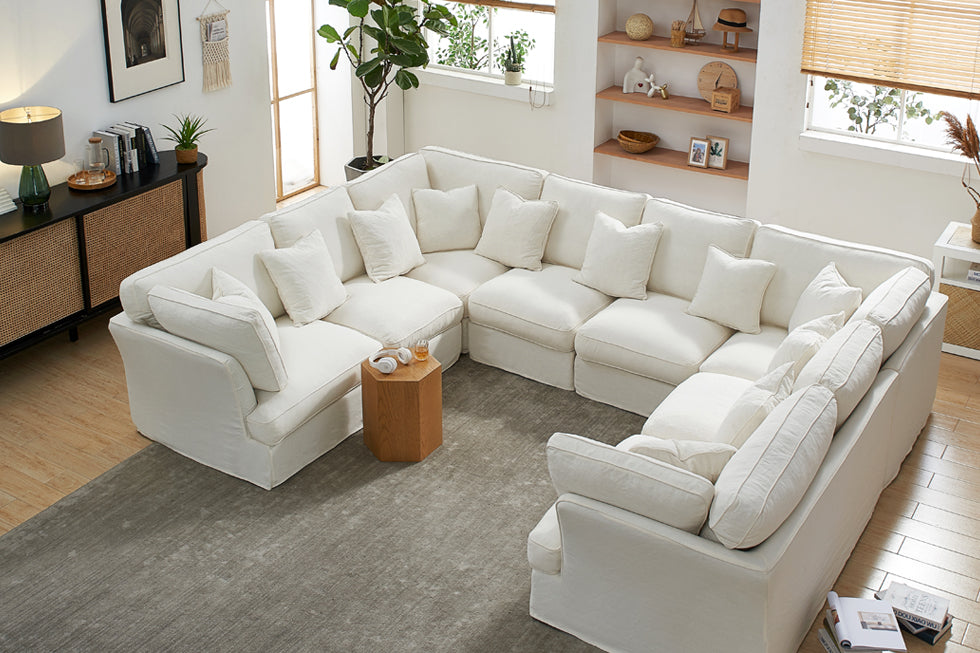 Living room setting with U-shape white sectional sofa and small wooden side table.
